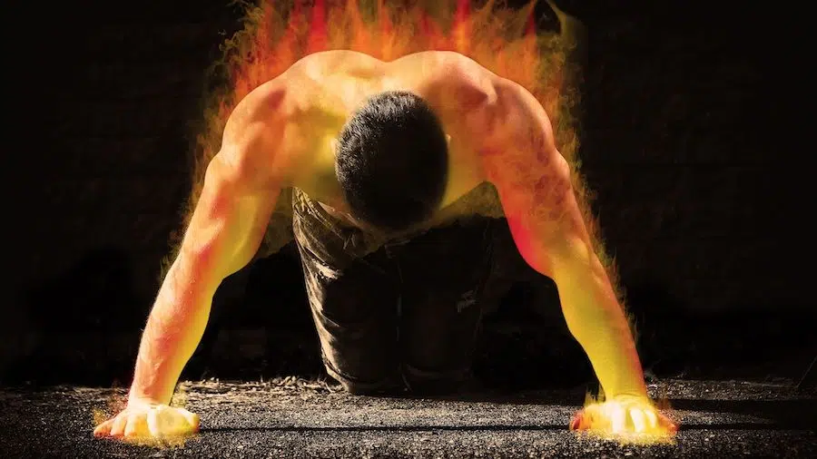 Un homme torse nu, à genoux avec les mains sur le sol, le corps en feu pour symboliser le fait qu'il se soit entraîné à l'échec musculaire.
