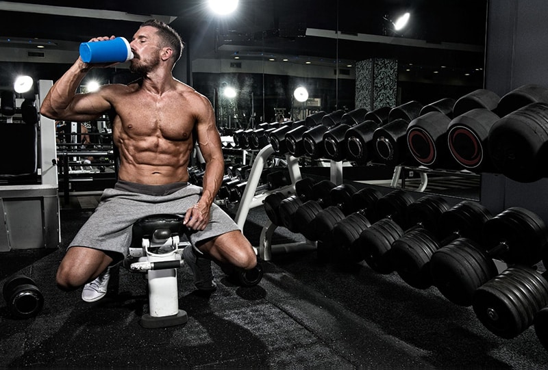 An athlete consuming a shaker of food supplements.