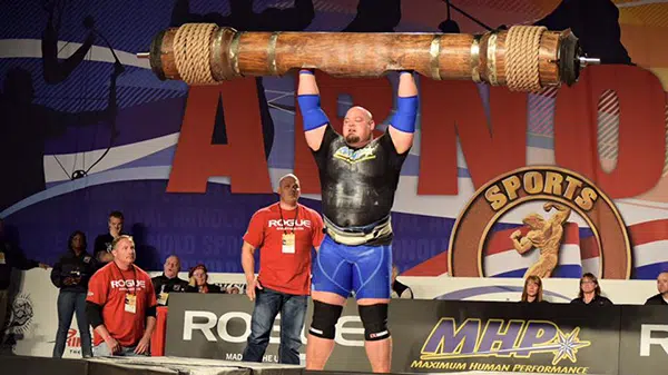 Le strongman américain Brian Shaw porte un tronc au-dessus de sa tête.