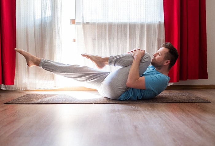 A man stretches his psoas lying on the floor.