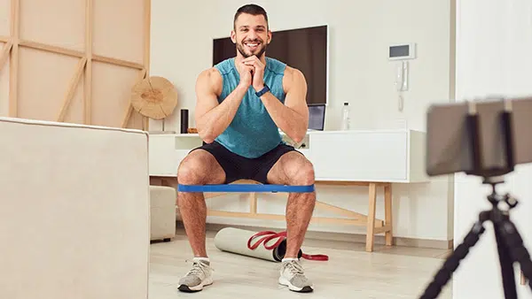 Un homme fait l'exercice du squat avec un élastique autour des genoux.