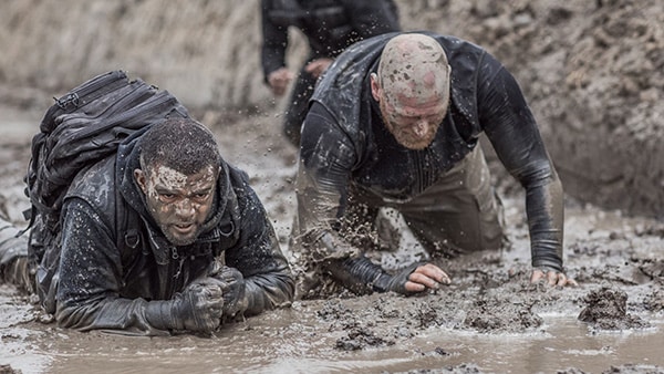 Des militaires allongés dans la boue lors d'un parcours d'obstacles.