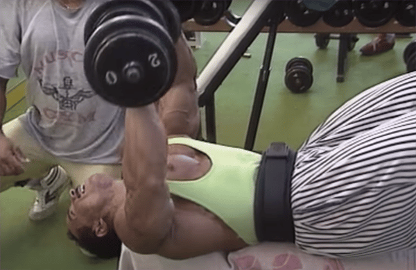 Mohamed Benaziza doing a dumbbell bench press in the weight room.