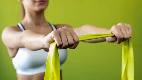 A woman performs a rotator cuff strengthening exercise with an elastic band.