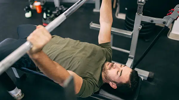 Un homme réalise l'exercice du développé couché dans une salle de musculation.