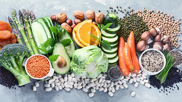 Un ensemble de fruits et de légumes à consommer pour maintenir votre équilibre acido basique : chou-fleur, carotte, salade, orange, noix, amandes, pois, avocat, etc.