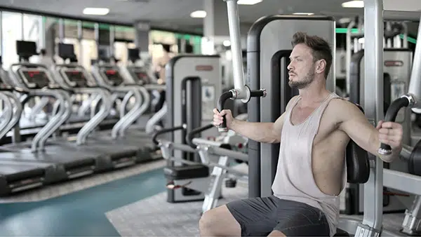 Un homme effectue un exercice de musculation pour les pectoraux dans une salle de sport.