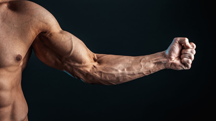 Un homme torse nu serre le poing et contracte son biceps pour voir apparaître sa veine du bras.