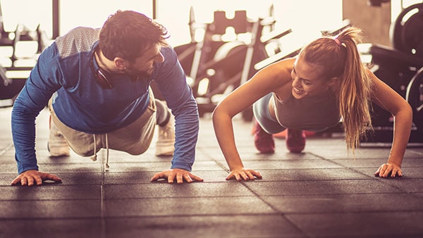 Un homme et une femme font l'exercice de musculation des pompes dans une salle de sport.