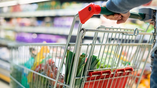 Une personne pousse un chariot plein d'aliments en faisant ses courses dans un supermarché.