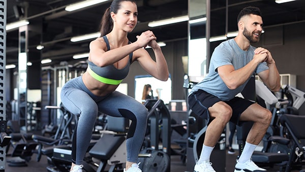 Une femme et un homme font de l'activité physique dans une salle de sport pour perdre du poids.