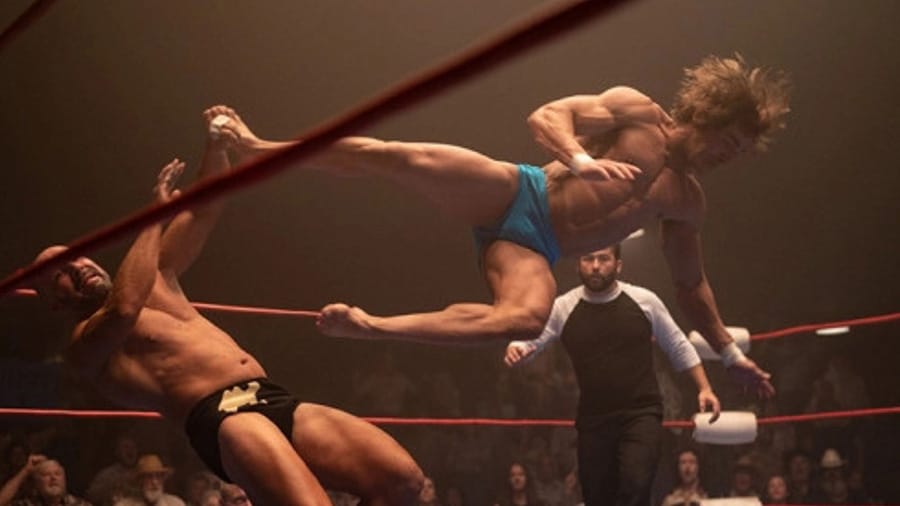 Une photo tirée du film The Iron Claw, dans lequel Zac Efron incarne un catcheur. Sur la photo, l'acteur effectue une prise de catch aérienne sur un ring et met au sol son adversaire.