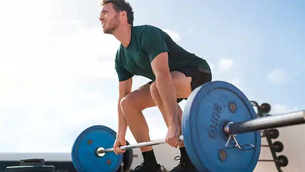 Un homme sportif réalise l'exercice de musculation du lever de terre, ou deadlift, pour travailler ses lombaires.