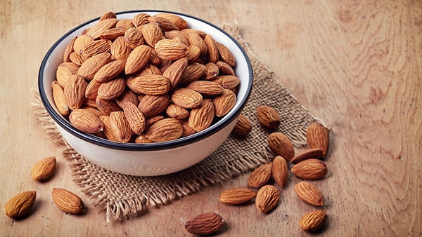 A bowl on a table, filled with almonds.