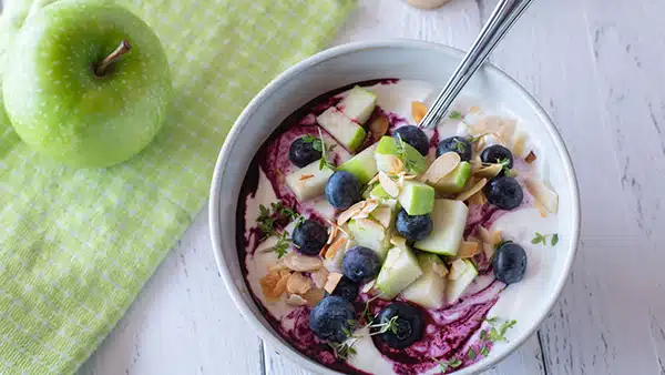 A bowl of fromage frais with fresh fruit (apple, blueberry, etc.).