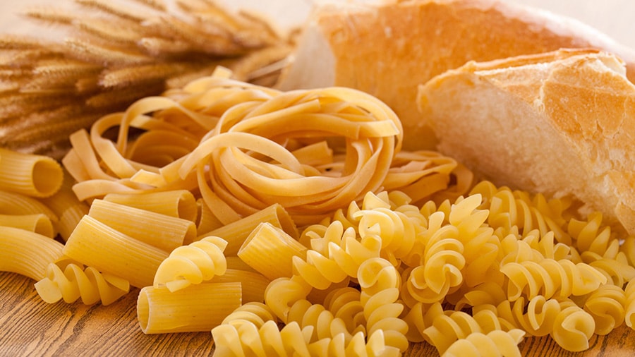White bread and pasta, two carbohydrate-rich foods, laid out on a table.