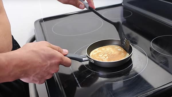 Sports coach Julien Quaglierini prepares protein pancakes in a frying pan.