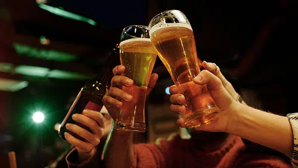 Des personnes en train de trinquer avec des verres de bière dans un bar.