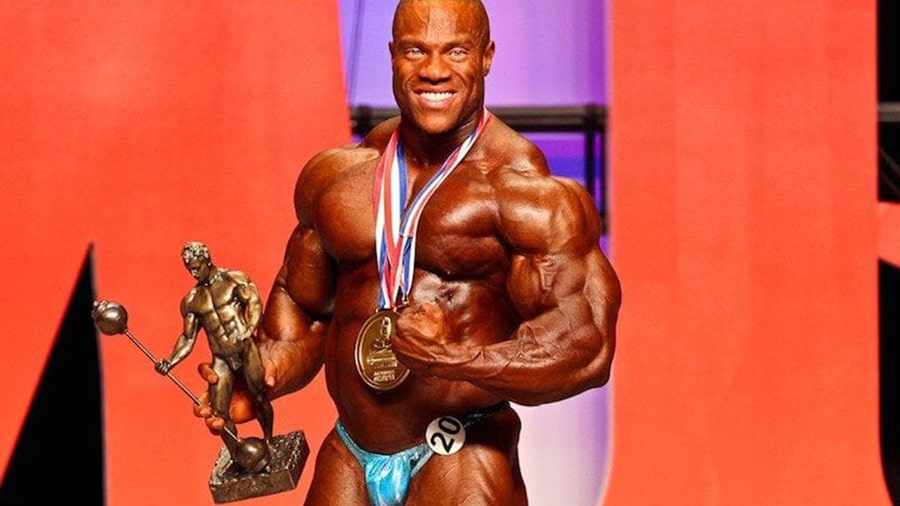Phil Heath after winning the Mr. Olympia contest, with his medal around his neck and his trophy in his right hand.