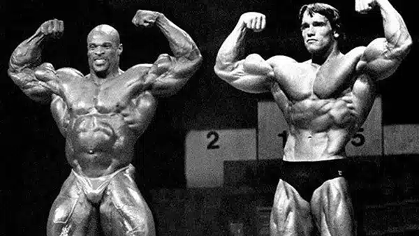 Les deux bodybuilders Arnold Schwarzenegger et Ronnie Coleman torse nu sur scène lors d'un concours de culturisme.