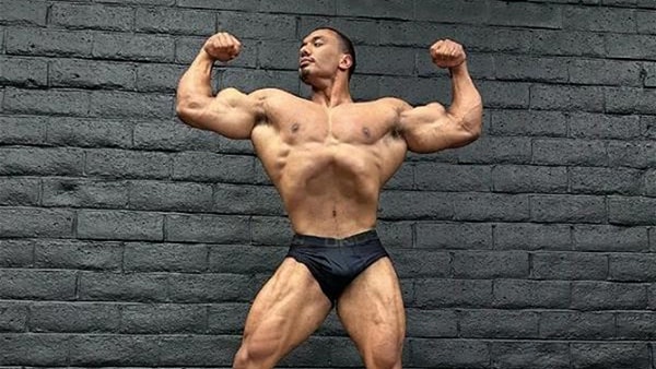 Le bodybuilder Larry Wheels torse nu, en train de faire un posing double biceps.
