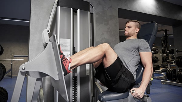 Un pratiquant de musculation fait de la presse horizontale pour renforcer ses jambes dans une salle de fitness.