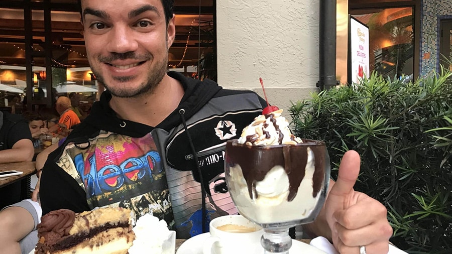 Le coach fitness Julien Quaglierini dans un restaurant, avec une coupe glacée et une part de gâteau devant lui.