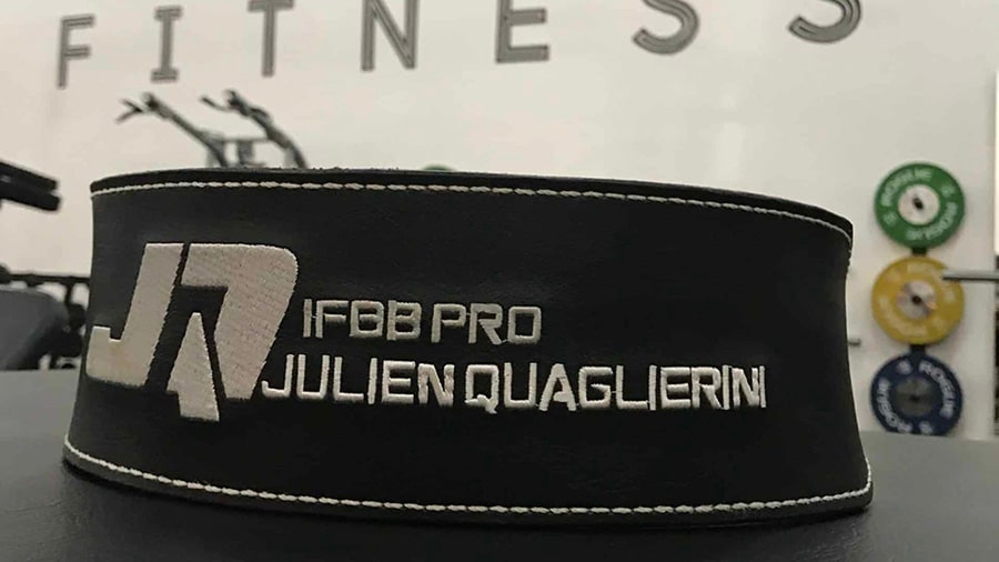 Une ceinture de force noire pour la musculation brodée de la mention "IFBB PRO JULIEN QUAGLIERINI".