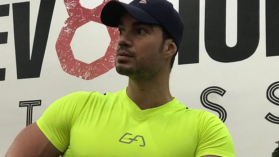 Le coach sportif Julien Quaglierini, avec un t-shirt jaune et une casquette, dans une salle de sport à Miami : Elev8tion Fitness.