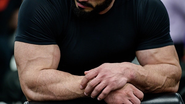 A man in a short-sleeved black T-shirt, with muscular arms.