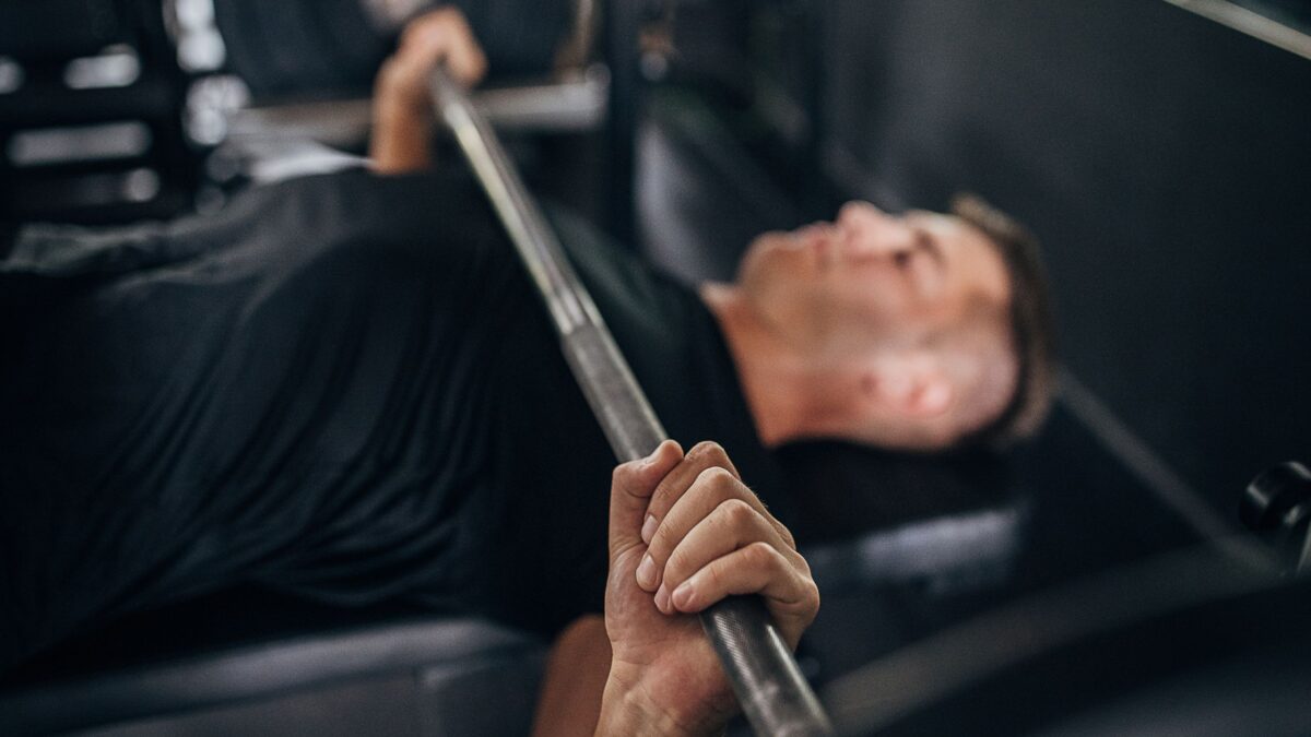 A man does a bench press at the bar in a gym.