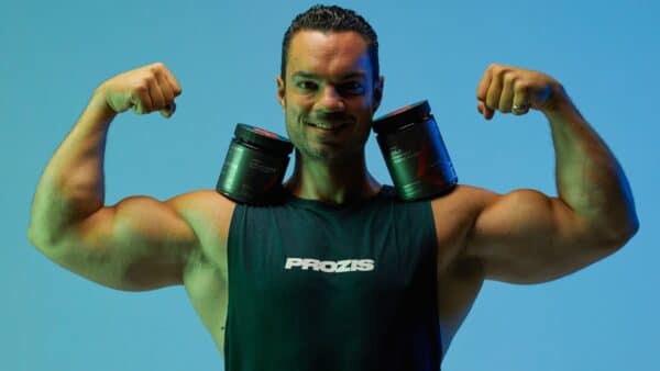 Sports coach Julien Quaglierini wearing a tank top from the Prozis dietary supplements brand and tensing his biceps.