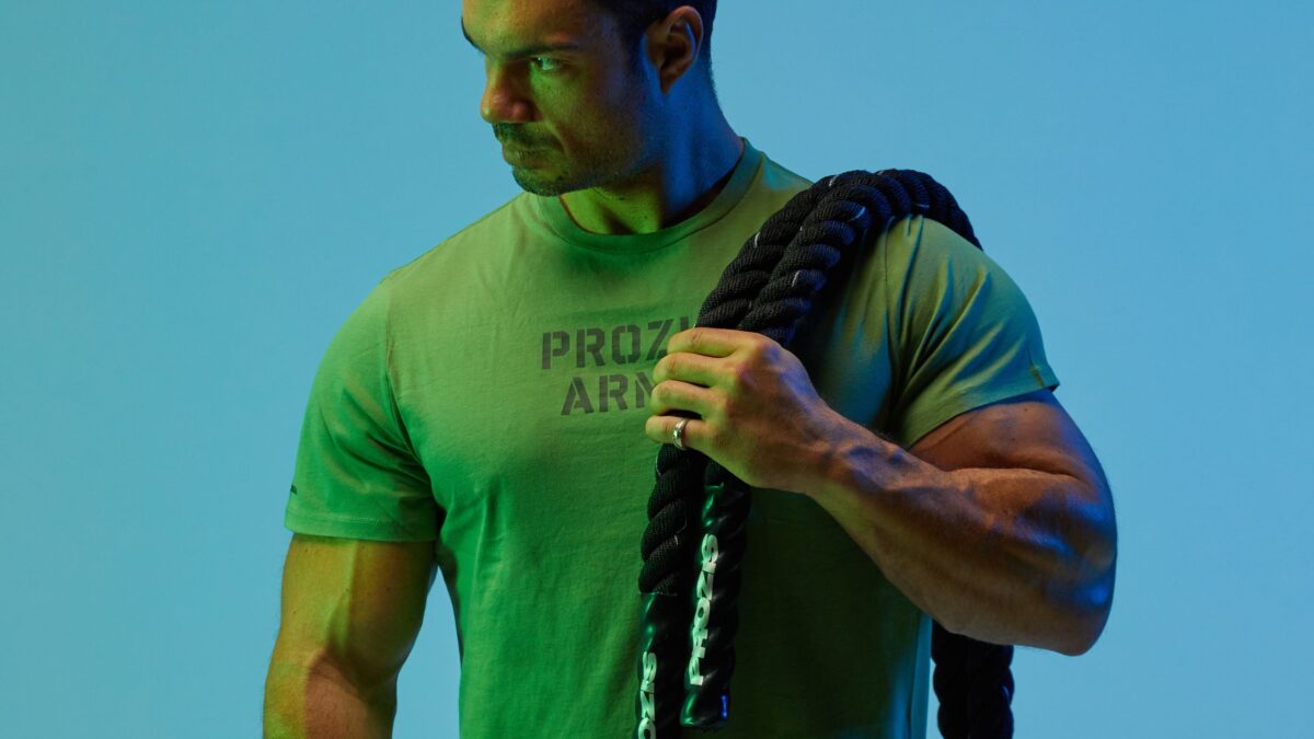 Une photo du coach sportif Julien Quaglierini, vêtu d'un t-shirt Prozis Army vert et portant une battle rope sur l'épaule.