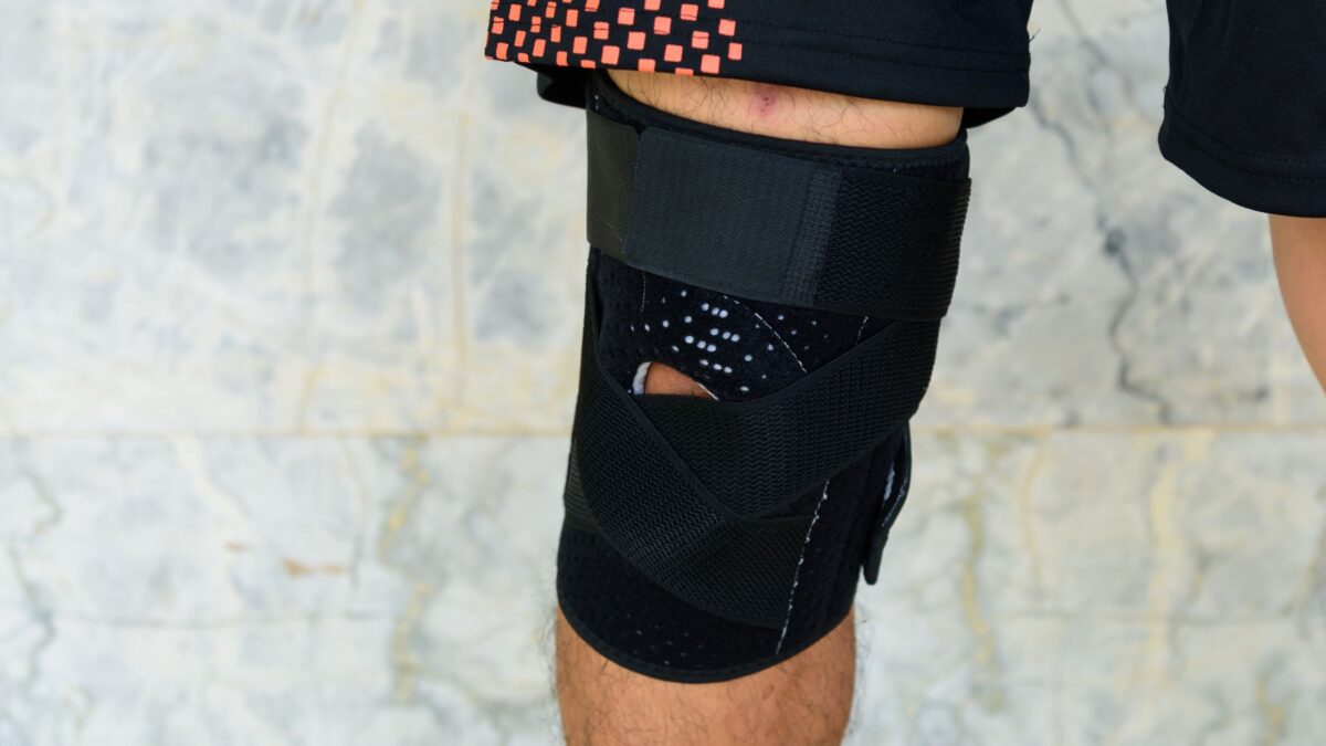 Un homme en short portant une genouillère de sport noire au genou droit.