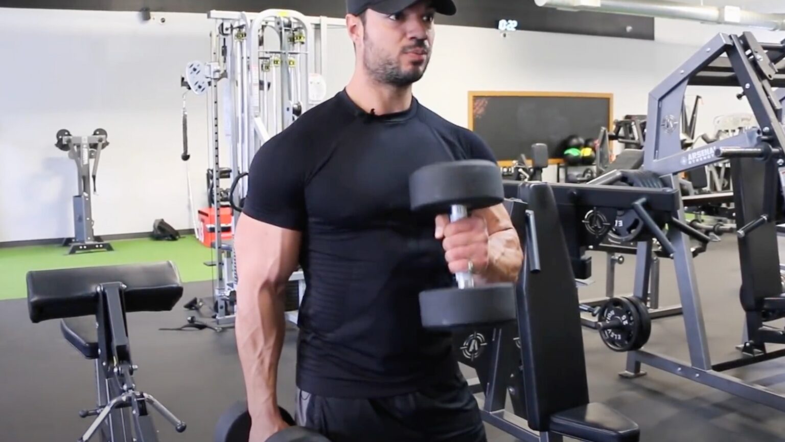 Le coach sportif et bodybuilder Julien Quaglierini fait du curl marteau aux haltères dans une salle de musculation.