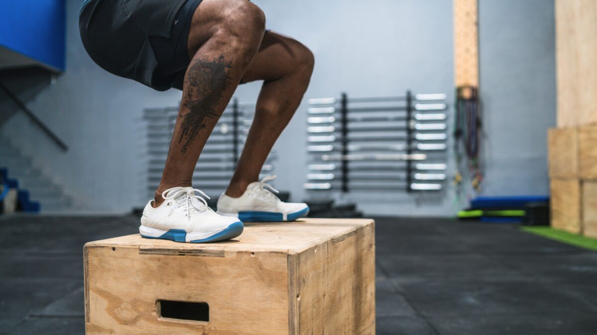 Un homme en short fait du jump box dans une salle de sport, un bon exercice pour renforcer ses genoux.