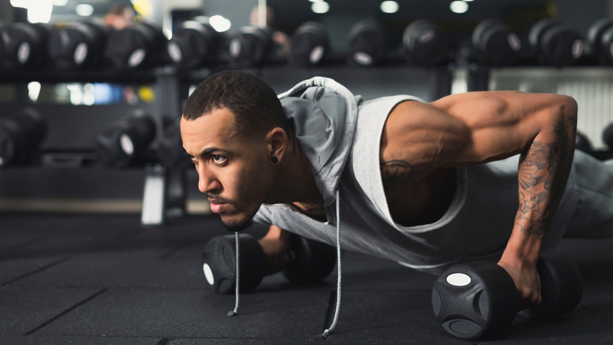 Un homme en tenue de sport fait des pompes dans une salle de musculation.