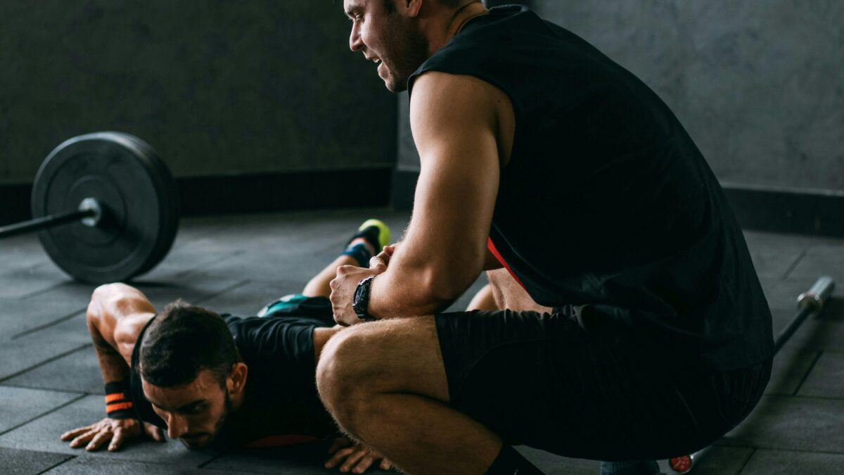 Deux hommes en tenue de sport s'entraînent dans une salle de musculation.